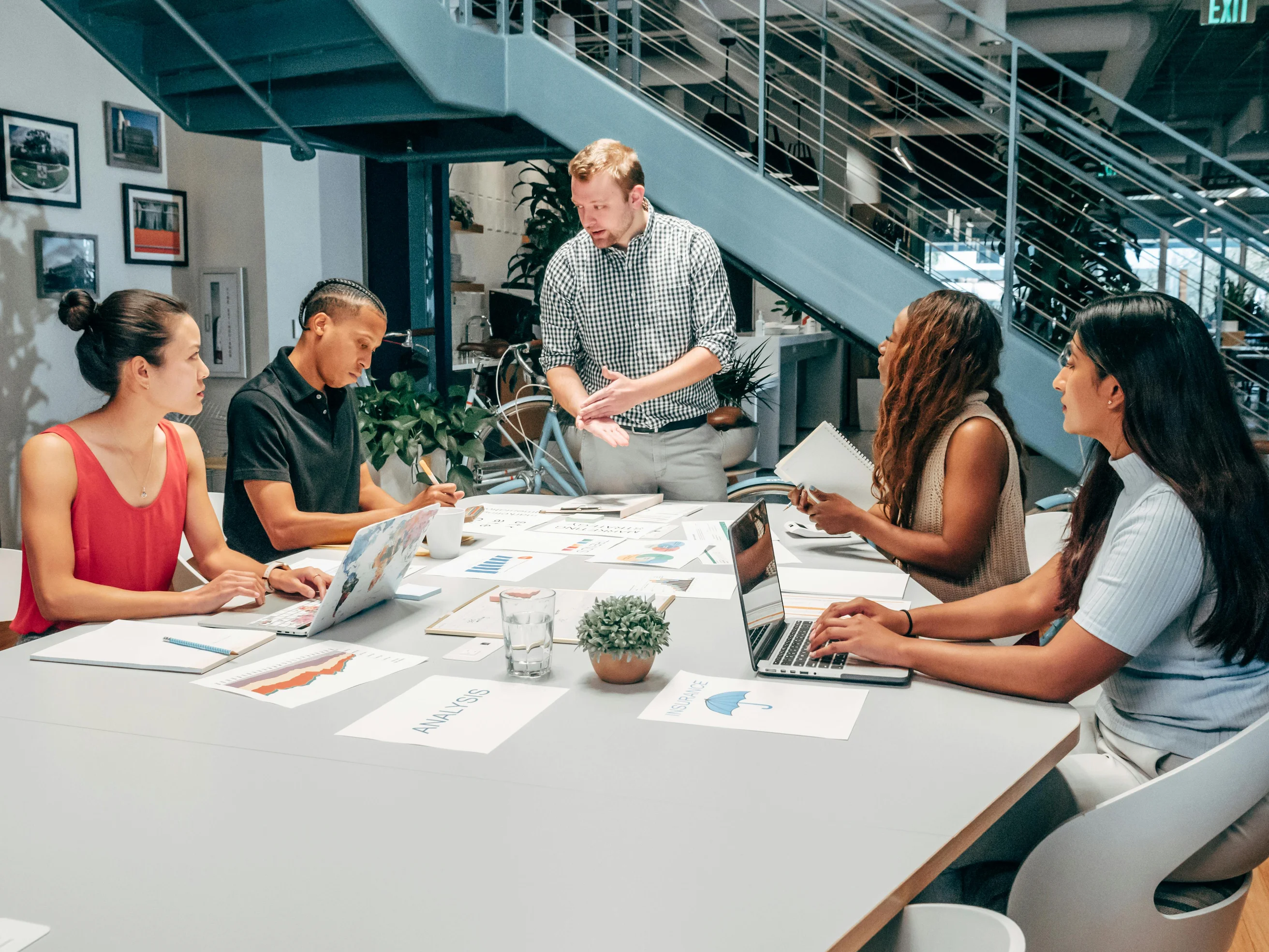 A diverse group of colleagues collaborating on a project in a modern office setting with laptops and documents.