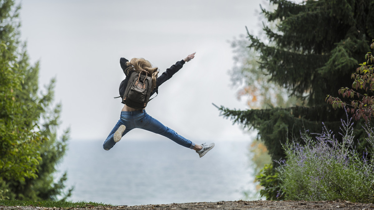 Woman jumping wearing green backpack