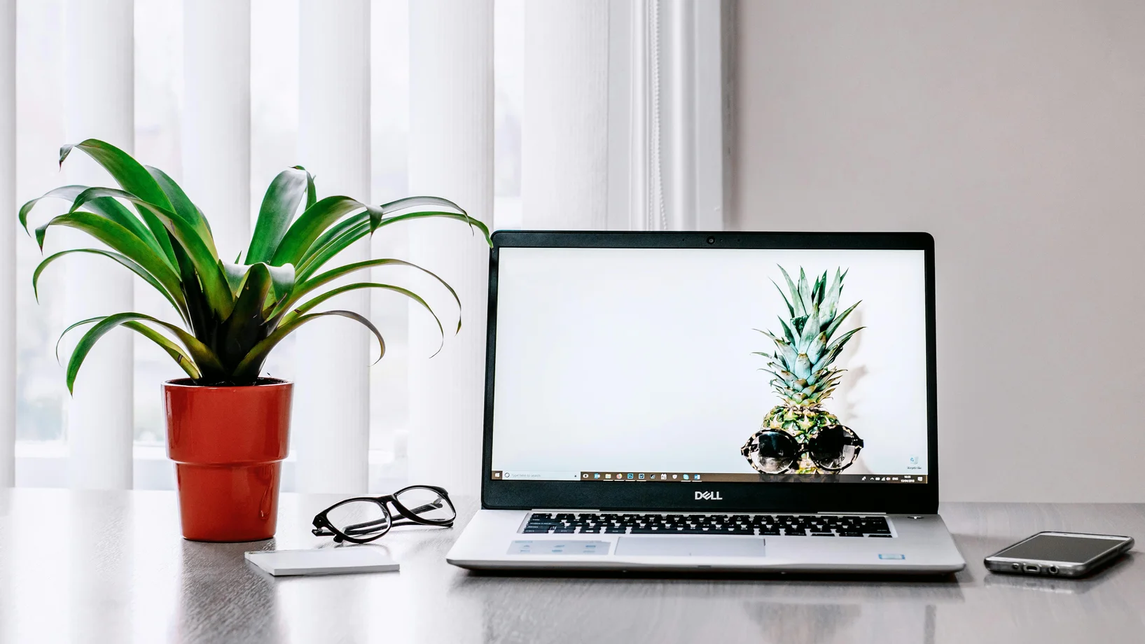 A stylish workspace featuring a laptop, plant, and smartphone on a desk.