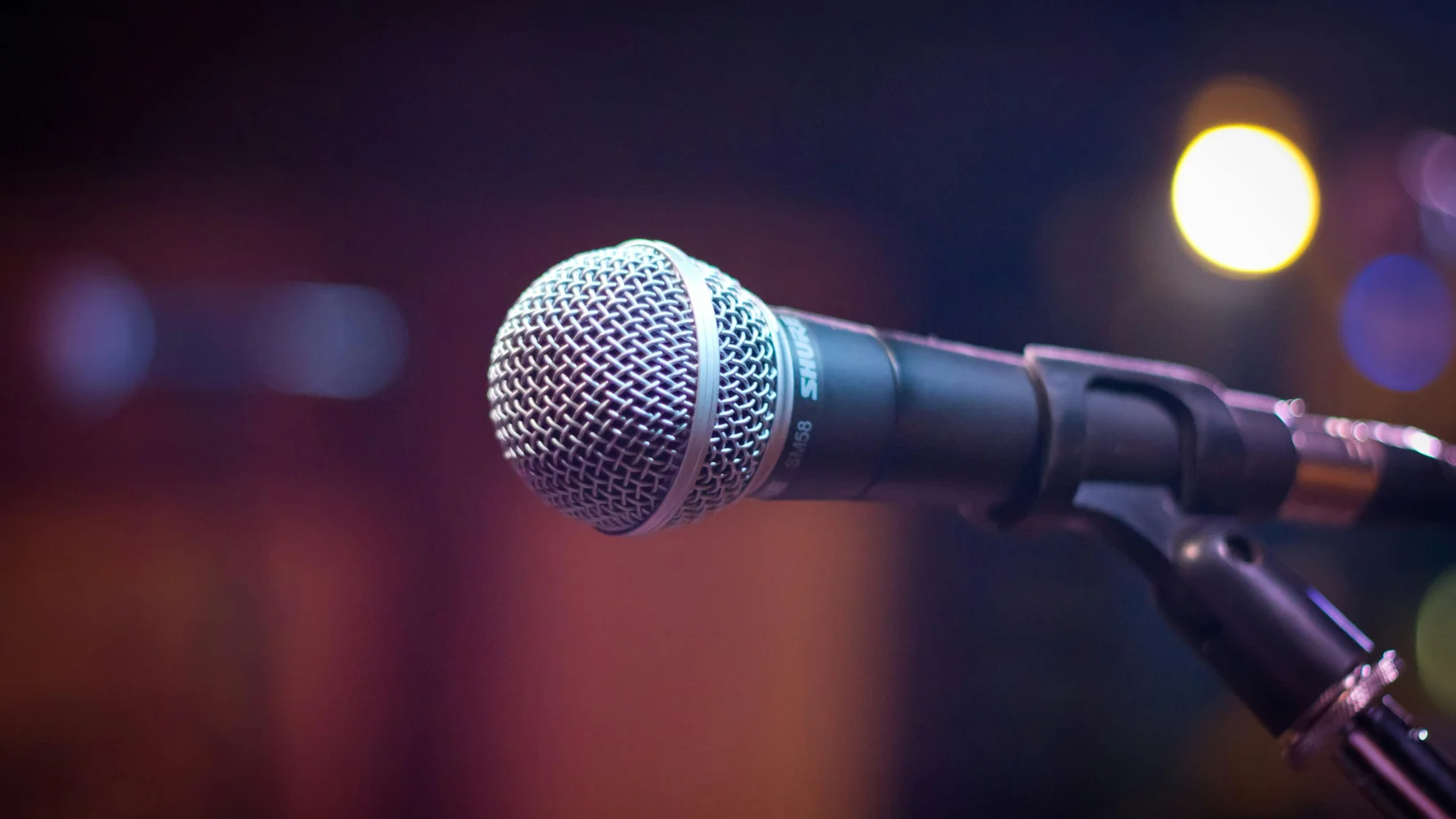 Dynamic microphone on stand with blurred stage lights in background.