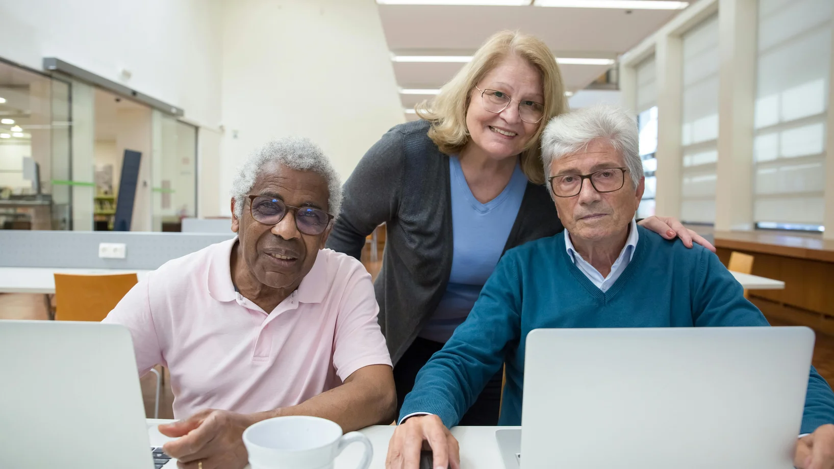 Elderly adults learning and enjoying computer class together indoors.