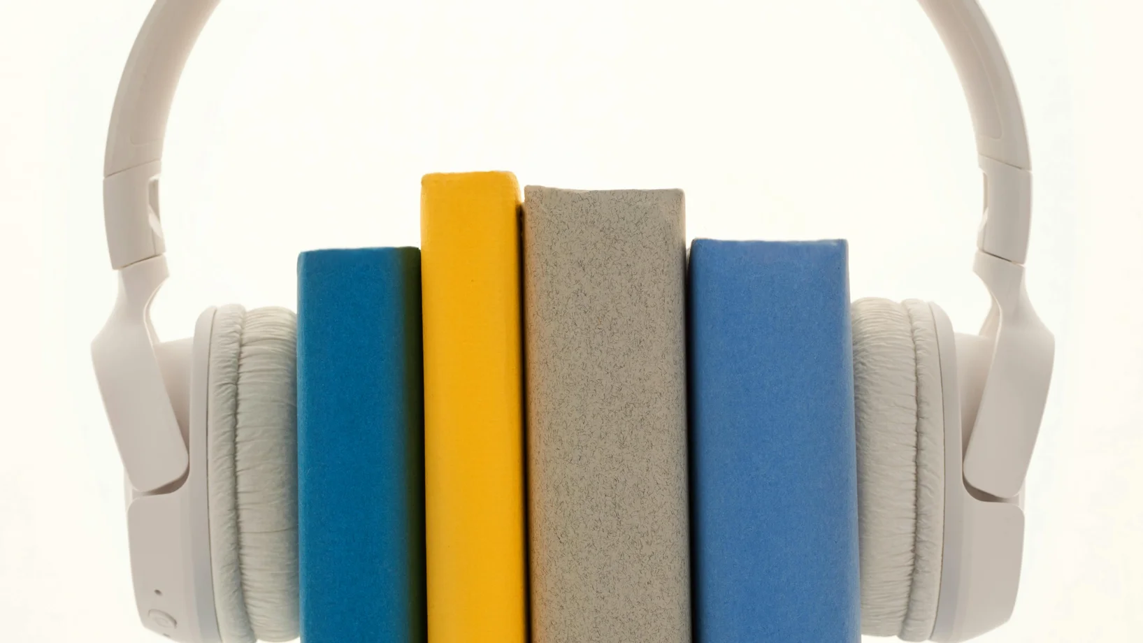 Creative concept of books wearing headphones, symbolizing audiobooks or learning.