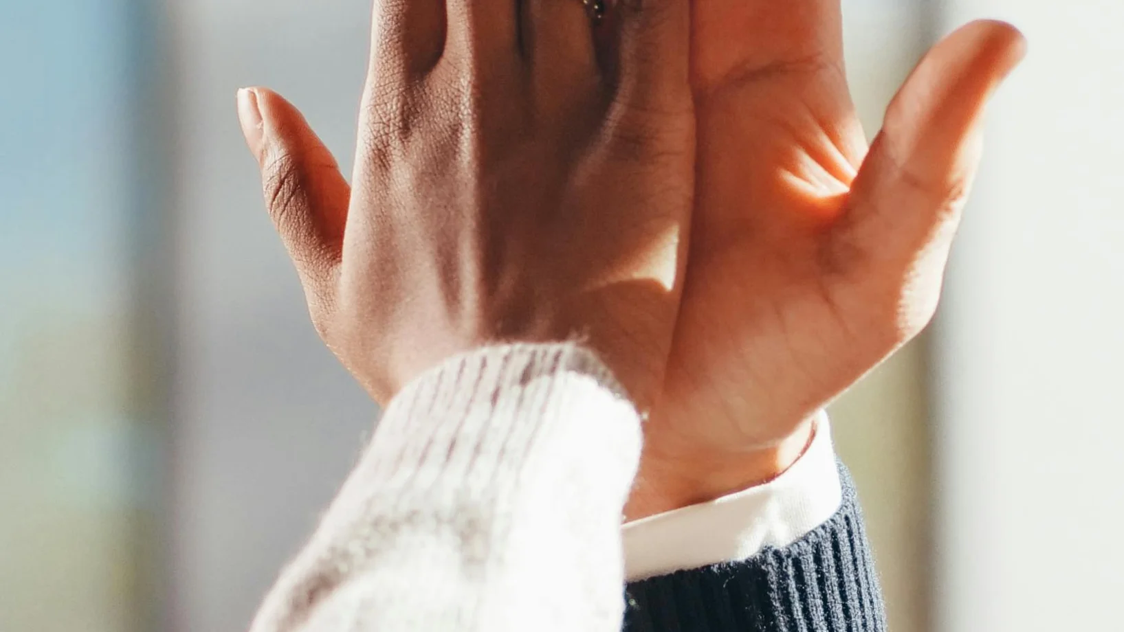 Close-up of two diverse people's hands high-fiving in a gesture of success and teamwork.