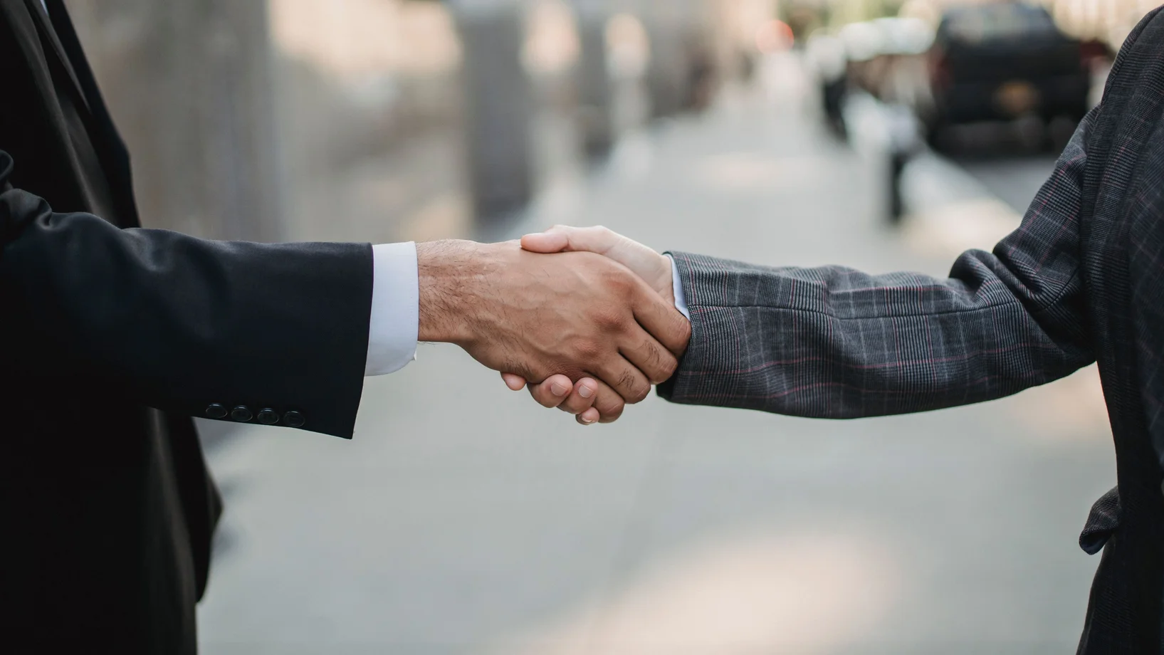 Close-up of a business handshake between professionals outdoors.